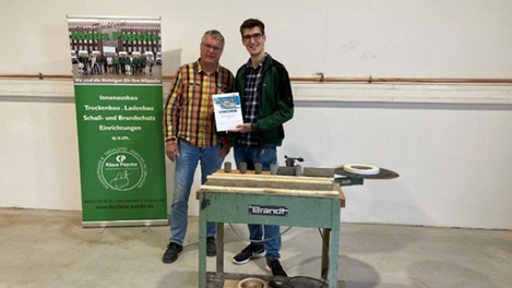 Il fondatore dell'azienda Klaus Papcke e il figlio Phil presentano la vincitrice, la bordatrice da tavolo T-50, a suo tempo un modello BRANDT, del 1978