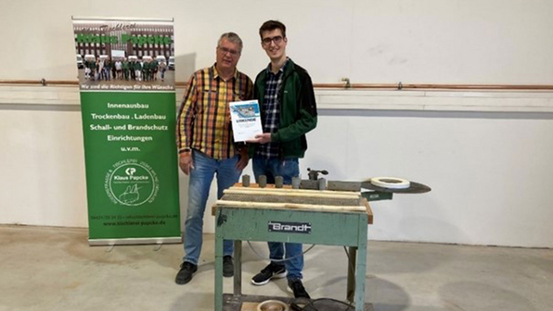 Founder Klaus Papcke and son Phil present their winning machine, the T-50 table edge banding machine, formerly a BRANDT model, from 1978