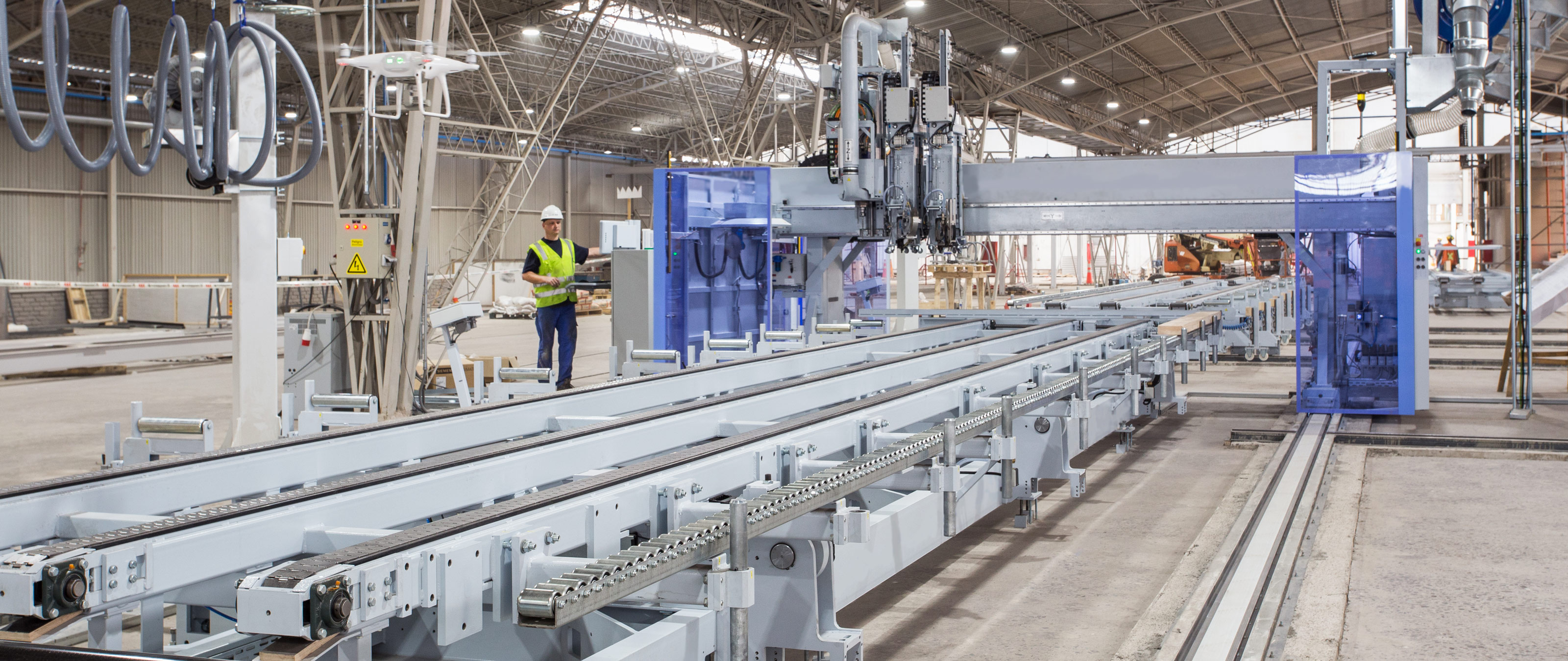 The production line includes a WALLTEQ M-380 multifunction bridge and three assembly tables.