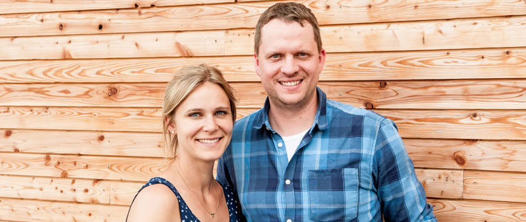 Marin Raindl zusammen mit seiner Frau posen vor ihrem Holzhaus.